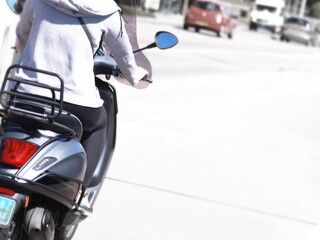 Rückenansicht einer Frau auf Motorroller