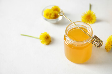 Jar with dandelion honey on white table