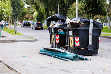 trash bins in disrepair in the middle of the street, noon, garbage on the street