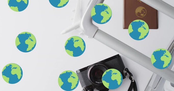 Animation of globes over suitcase, passport, camera and plane model on white background