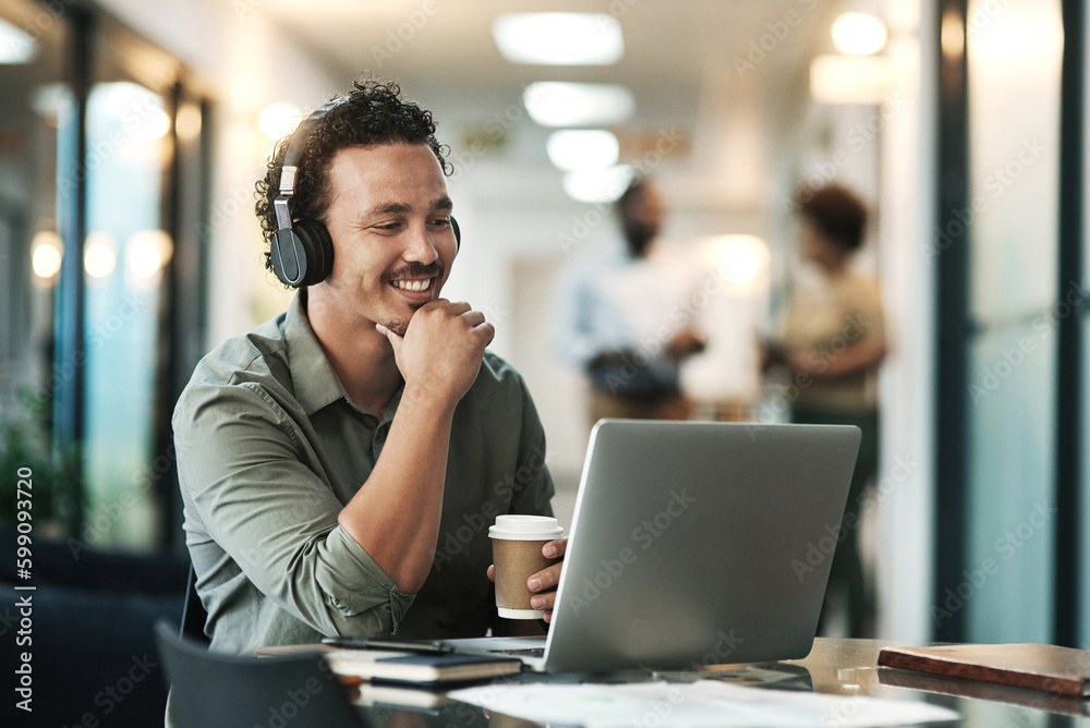 Wall mural Listening is part of the planning process. a young businessman sitting in the office and wearing headphones while using his laptop for a virtual meeting.