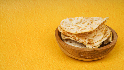 Tempe chips served on a wooden plate with a yellow background