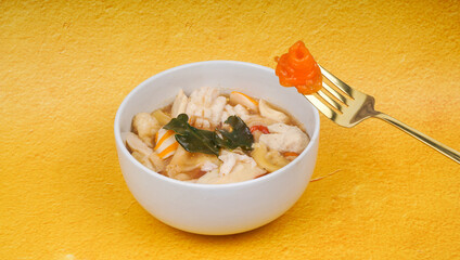 Indonesian Traditional spicy hot savory food Seblak Jeletot with golden fork. It's served on white bowl