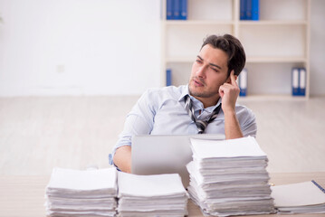Naklejka premium Young male employee and too much work in the office