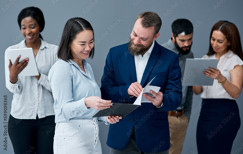 Poster reaching resolutions faster together. two businesspeople going through paperwork while their colleag