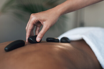 Hot stones rejuvenate the body. Closeups shot of an unrecognisable woman getting a hot stone massage at a spa.
