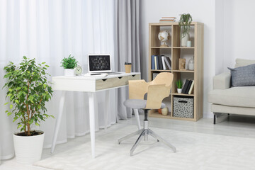 Fototapeta na wymiar Workplace with modern laptop on desk and comfortable chair at home