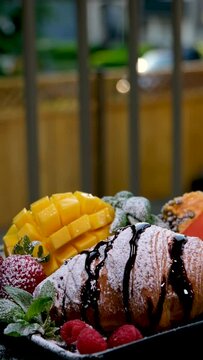 delicious french breakfast croissant with chocolate and powdered sugar on a black plate in a restaurant on the street Mango fruit berries raspberry strawberry papaya mint beautiful serving morning
