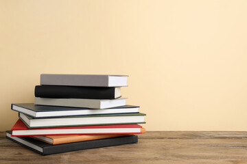 Stack of hardcover books on wooden table, space for text
