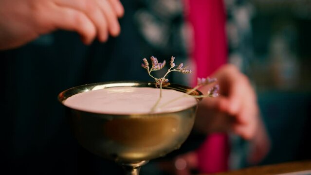 a professional bartender decorates a freshly prepared cocktail with flowers at the bar