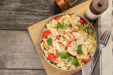 Delicious pasta with tomatoes, basil and parmesan cheese served on wooden table, flat lay. Space for text