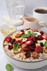 Oatmeal with freeze dried fruits, nuts and mint on white table