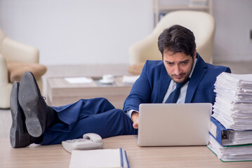 Young male employee and too much work in the office