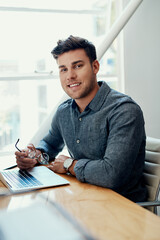 Welcome to my workspace. Cropped portrait of a handsome young businessman sitting alone and using his laptop in the office.