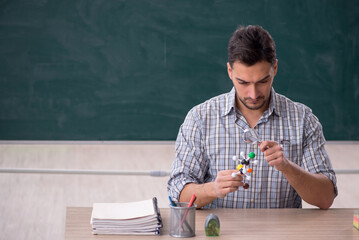 Young male teacher holding molecular model