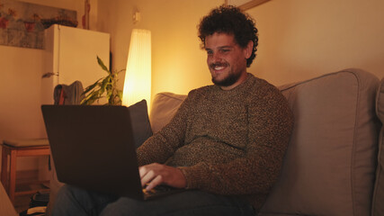 Young man sitting in the living room on the sofa with laptop