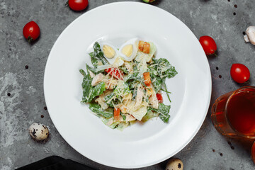 Traditional caesar salad in a white bowl on a old white table with leaves and a sauce boat and parmesan. Selected focus.