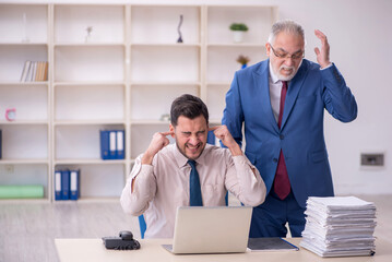 Old male boss and young male employee in bullying concept