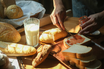 Cropped shot of man spreading tasty  strawberry jam onto bread in kitchen.