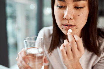 This will make me feel better. a young businesswoman taking medication in an office.