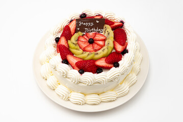 Homemade birthday cake decorated with strawberries, kiwi fruit and blueberries isolated on white background in top view.