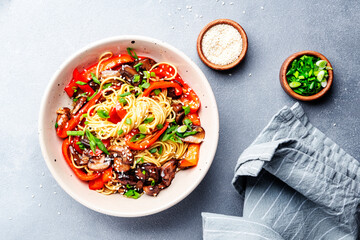 Vegan stir fry noodles with vegetables, paprika, mushrooms, chives and sesame seeds in bowl. Asian...