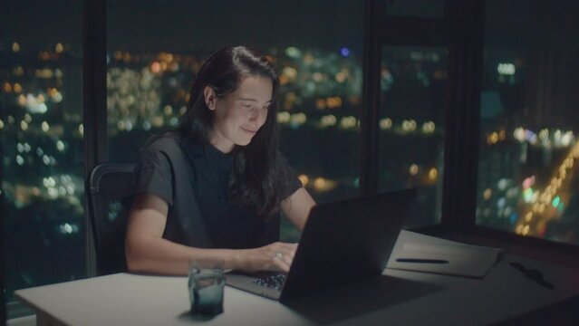 Medium shot of white woman writer working and typing poetry at night