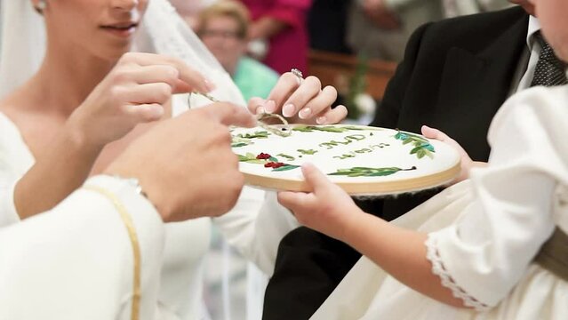 Bride With White Dress Unlacing Ribbon Taking Out Wedding Ring From Little Bridesmaid