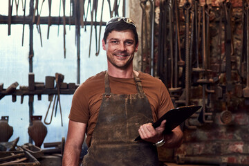 Smart tools and devices are also needed in the workshop. Portrait of a handsome young craftsman using a digital tablet while working inside a metal workshop.