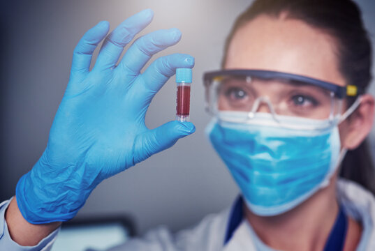 So this is the end result. Closeup of an unrecognizable female scientist wearing a protective face mask and holding up a vile of blood inside of a laboratory.