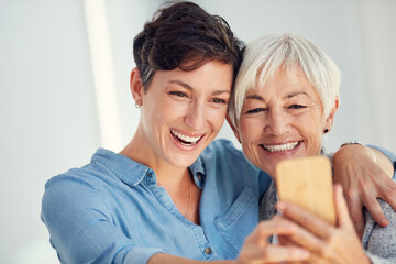 Lets capture our beautiful smiles. an affectionate young woman taking a selfie with her aged mother at home.