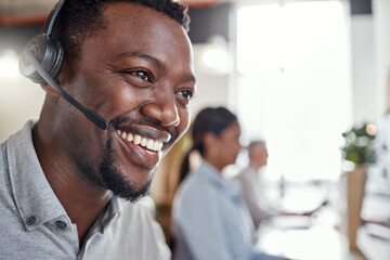 The friendly face behind the phone. a young man using a headset in a modern office.