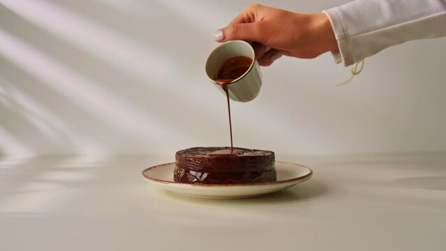 delicious freshly made chocolate sacher cake on a plate on a white background drizzled with hot chocolate dessert concept