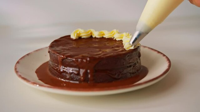 delicious freshly made chocolate Sacher or Prague cake on a white background decorated with cream from a pastry sleeve