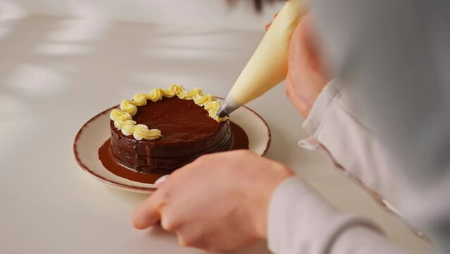 delicious freshly made chocolate Sacher or Prague cake on a white background decorated with cream from a pastry sleeve