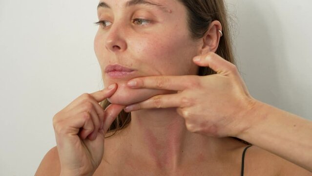 de cerca retrato cabeza mujer joven caucasica practicando ejercicios de yoga facial en estudio
