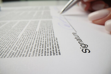 Woman puts personal signature above line on paper sheet