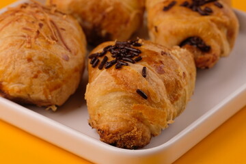 Bolen pisang is a typical Bandung food which containsripe banana, wrapped in pastry, topped with cheese or chocolate. Indonesian food. isolated on yellow table. 