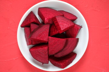 Beta vulgaris. sliced beetroot on a white ceramic plate on red table. golden beet or red beet. red...
