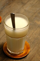 soursop juice in a clear glass. melted chocolate. fresh drink from tropical fruit. wooden table.