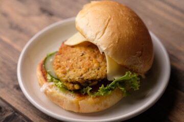 Burger Tempe is burger with tempeh filling. Bun bread, stuffed with processed tempeh, sliced cheese, sliced tomatoes, lettuce, mayonnaise, and tomato sauce. healthy burgers, suitable for vegans. Diet