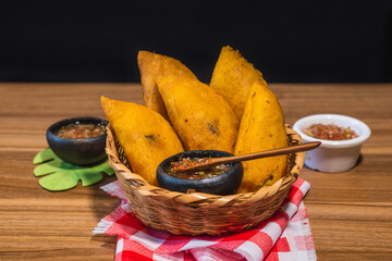 Colombian empanadas. Table with traditional Colombian food, wicker basket with empanada con aji, on...