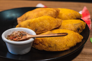 close up dish with empanadas with chili pepper on a table. Colombian traditional food. wood background