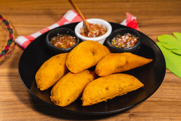 plate with empanadas with chili pepper on a table. Colombian traditional food. wooden background