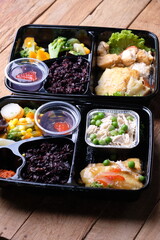 healthy food bento with black rice, dori fish fillet, vegetable soup, shredded chicken, and fruit...