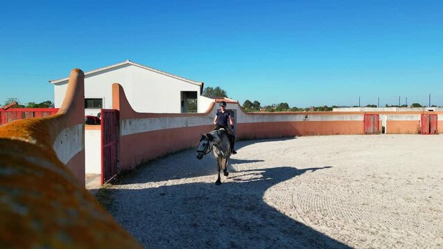 Static image of a young girl riding a Lusitano horse in a Lusitano tentadero.
