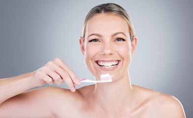 Brush twice daily to maintain your pearls. Studio portrait of an attractive mature woman brushing her teeth against a grey background.