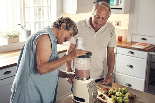 Its all blended. a senior couple making a smoothie in the kitchen at home.