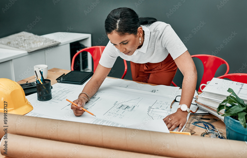 Poster working on a new design. a young architect working with blueprints in an office.