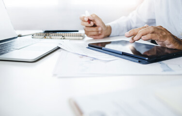 Businessman using tablet and laptop computer contact business search information on desk at home office checks mail, analyzing investment plan, conducts business correspondence with customers